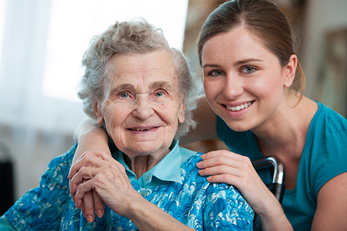 Grandmother and daughter both wearing blue and smiling at the camera